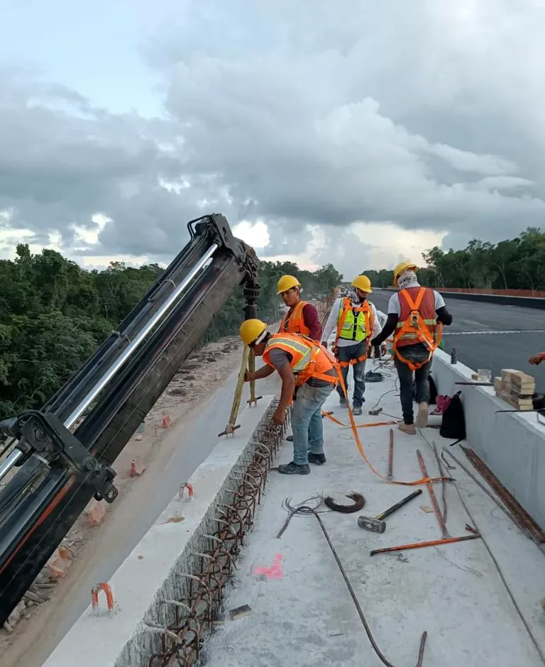 Personal técnico con arnés y casco trabajando sobre la losa de un puente